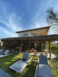 a villa with two lounge chairs and a house at Beach House Brazil in Amontada