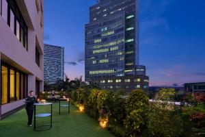 a man standing on a rooftop patio with a building at Mandarin Oriental, Jakarta in Jakarta