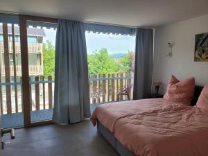 a bedroom with a bed and a balcony with a view at LakeSide - exklusives Architektenhaus C5 mit Seesicht auf der Höri in Öhningen