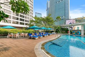 a swimming pool with lounge chairs and umbrellas in a city at Mandarin Oriental, Jakarta in Jakarta