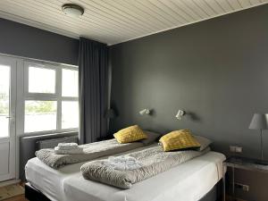 霍尔斯沃德吕尔Ármót Guesthouse的一间卧室，有两张床，配有黄色枕头