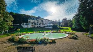 una grande casa con una fontana in mezzo a un parco di Hotel Bel Air Trail & Wellness a Echternach