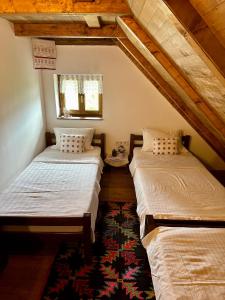 2 Einzelbetten in einem Zimmer mit einem Teppich in der Unterkunft Bobića konak - Lukomir in Lukomir
