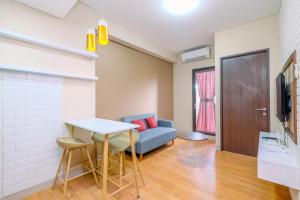 a living room with a blue couch and a table at Best Deal and Comfortable 2BR Transpark Cibubur Apartment near Mall By Travelio in Depok