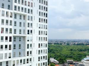 a tall white building next to another building at Great Choice and Comfort Stay 2BR at Patraland Urbano Apartment By Travelio in Bekasi