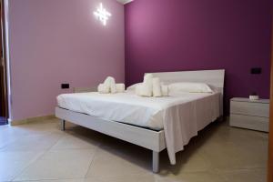 a bedroom with a white bed with a purple wall at Maccuro Luxury Apartment in Vibo Valentia Marina