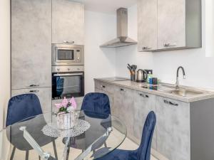 a kitchen with a glass table and blue chairs at Apartment Nina by Interhome in Novi Vinodolski
