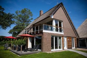 a brick house with a large window and patio at Residenz - Sonnenglut - Seeterrasse - Sauna - Parkplatz in Bad Zwischenahn +19 photos