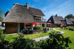 a house with a thatched roof with tables and chairs at Residenz - Wellenreiter - Penthouse - Sauna - Parkplatz in Bad Zwischenahn