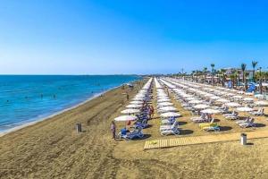 a beach with chairs and umbrellas and the ocean at Airbnsea City Centre Side Sea View Apartments in Larnaka +240 photos