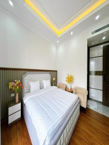 a bedroom with a large white bed and a chair at Villa 13 phòng ngủ vip - Đầy đủ tiện nghi - Bể bơi riêng - Bàn Bi a in Ha Long +15 photos
