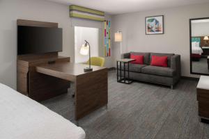 a hotel room with a bed and a desk with a television at Hampton Inn and Suites Seattle - Airport / 28th Avenue in SeaTac +18 photos