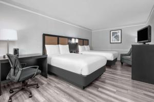 Una habitación de hotel con dos camas, un escritorio y una silla. en Baymont by Wyndham Austin University Area, en Austin