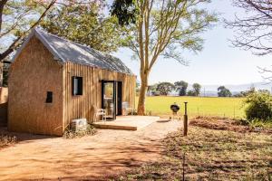 a small wooden house in a field with a tree at Modern Cabin in Malkerns in Malkerns