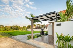 une pergola sur le côté d'une maison avec une cour dans l'établissement The Lavana Bliss One Villa Nyanyi Beach, à Canggu