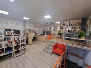 a library with a red chair in a room at Capsule Hostel Logistic Vilnius in Vilnius