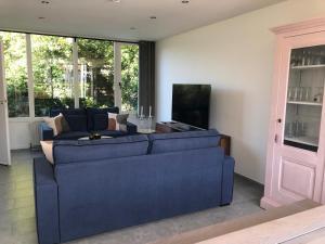 a living room with a blue couch and a tv at Crevette, vakantiehuis voor 6 personen in Middelkerke
