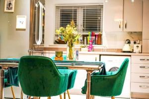 a kitchen with green chairs and a table with a vase of flowers at Private Double room in a 2 bed shared new build flat, Reading in Shinfield
