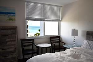 サラソタにあるPrivate Beach Condo On Lido Keyのベッドと椅子2脚と窓のある寝室 +33枚の写真