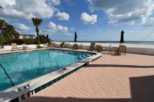 サラソタにあるPrivate Beach Condo On Lido Keyの背景にビーチと椅子付きのスイミングプール