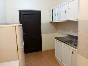 a kitchen with white cabinets and a black door at صاري in Jeddah