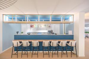 a bar with a row of stools in a restaurant at Tuscany Hotel Alle Dune in Marina di Castagneto Carducci