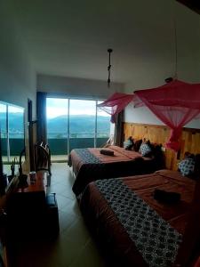 two beds in a room with a large window at Polo Region Rest Inn in Haputale