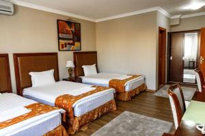 a hotel room with three beds and a table at Boutique Hotel IGMAS, Prishtina in Prishtinë