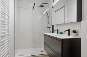 ein weißes Badezimmer mit Waschbecken und Dusche in der Unterkunft Triton luxe gelijkvloers appartement met tuin en gratis garage in Knokke-Heist + 11 Fotos