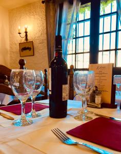 a bottle of wine sitting on a table with wine glasses at Logis Hôtel Restaurant Le Top du Roulier in Capendu