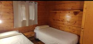 a bedroom with two beds in a log cabin at Camping La Vall d'Hostoles in Sant Feliu de Pallerols
