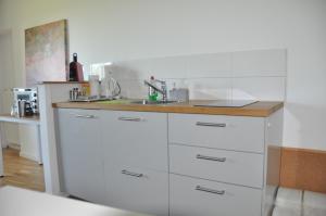 a white kitchen with a sink and a counter at 2-ZIMMER WOHNUNG mit TERRASSE, FERNBLICK, NATUR, RUHIG - Marburg in Marburg an der Lahn
