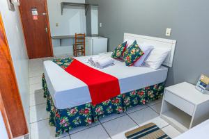 a small bedroom with a bed with a red blanket at Teuthos Hotel in Teutônia