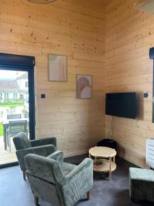 a living room with chairs and a flat screen tv at Les Chalets près de Chalain in Montigny-sur-lʼAin