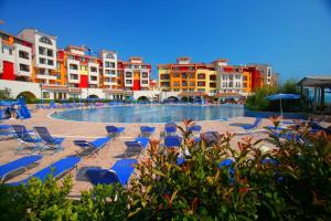 a swimming pool with blue lounge chairs and buildings at Марина Кейп in Aheloy