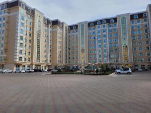 a large building with cars parked in a parking lot at квартира in Aktau