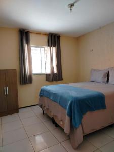 a bedroom with a bed with blue sheets and a window at Casa Ubajara in Ubajara