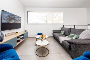 ein Wohnzimmer mit Sofa und Fernseher in der Unterkunft Villa Azénor Bretagne Piscine Intérieure Partagée toute l'année 100m plage in Sibiril