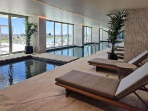 a swimming pool in a building with chairs and plants at DLux Terrace Cond Bayline Pool & SPA in Armação de Pêra