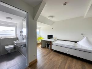 a bedroom with a bed and a sink and a bathroom at Rosa Flesch Hotel und Tagungszentrum in Waldbreitbach