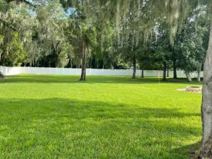 a field of green grass with trees and a fence at Downtown Dade City Glamper in Dade City
