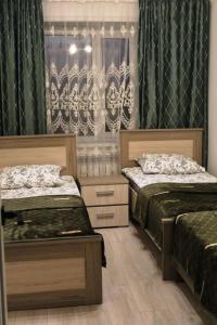 a bedroom with two beds and a window with curtains at Дом в Бурабай in Borovoye