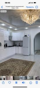 a white kitchen with a refrigerator and a chandelier at Дом в Бурабай in Borovoye +21 photos
