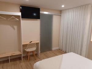 a bedroom with a bed and a desk and a television at Pensión Vázquez in Vimianzo