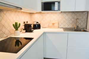 una cucina con mobili bianchi e un lavandino di Sunshine Apartment - Appartamento Vicino al Mare, Cagliari, Sardinia a Cagliari