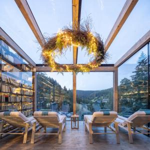 a room with a large window with chairs and a chandelier at Pytloun Wellness Hotel Harrachov in Harrachov