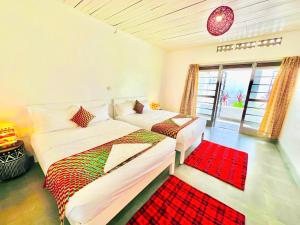 a bedroom with two beds and a red rug at KaChai Hotel Fort Portal in Kyarusozi