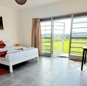 a bedroom with a bed and large sliding glass doors at KaChai Hotel Fort Portal in Kyarusozi