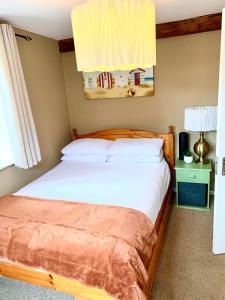 une chambre avec un lit avec des draps blancs dans l'établissement Daisy Cottage, à Child Okeford