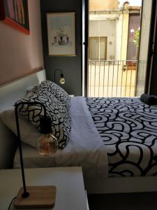 een slaapkamer met een bed met een zwart-wit dekbed bij Kalos Rooms in Agrigento +3 foto's